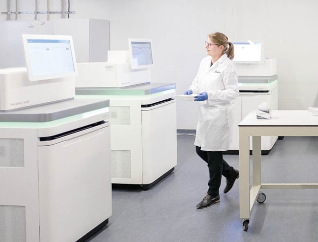 Wissenschaftlerin arbeitet im Labor für humangenetische Diagnostik mit fünf NovaSeq 6000 Sequenziergeräten